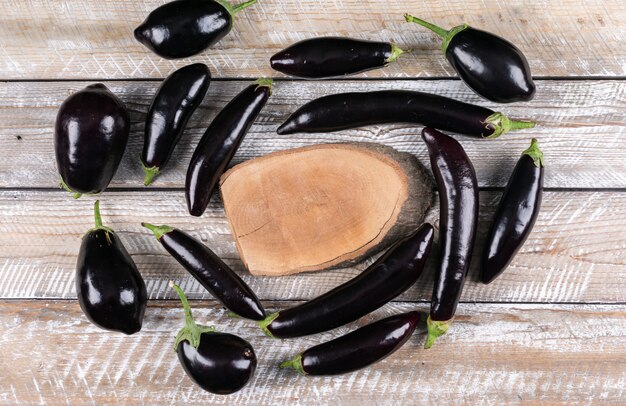 Circle forming eggplants around wood on a wooden . top view.