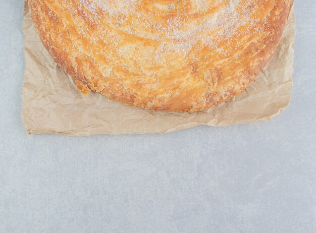 Circle pastry decorated with white powder on sheet.