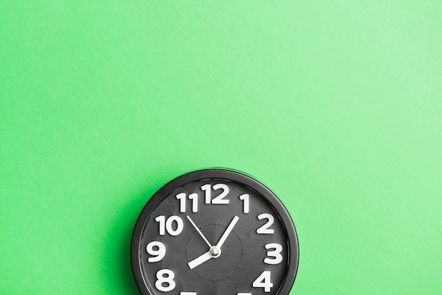 Free photo circular black clock on green wall backdrop