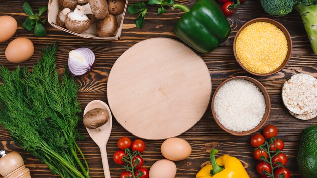 Circular chopping board with fresh vegetables on table