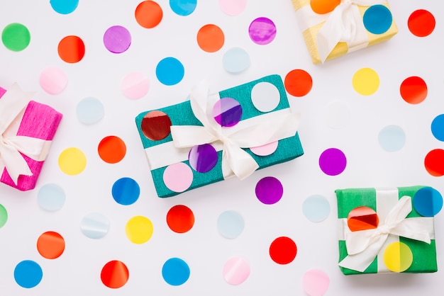 Circular colorful confetti on gift boxes against white background