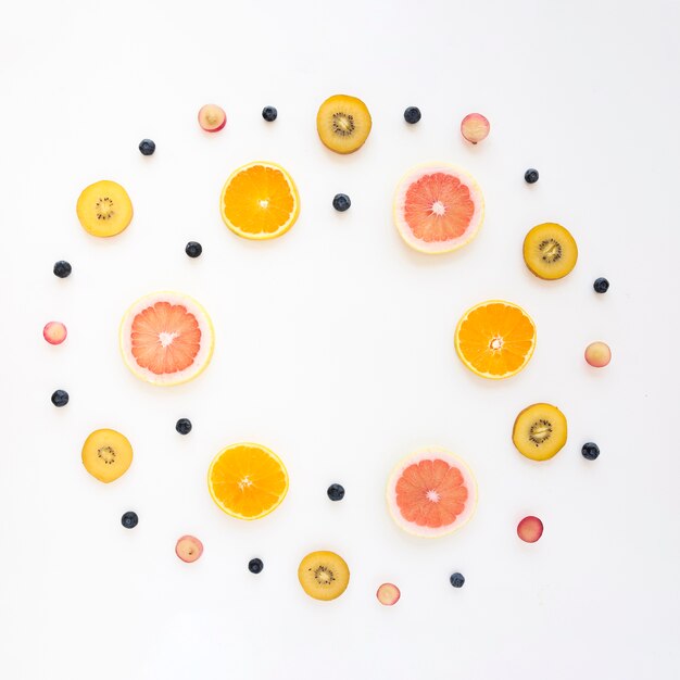 Circular frame made with orange; grapes; kiwi; grapefruit and blueberries on white background