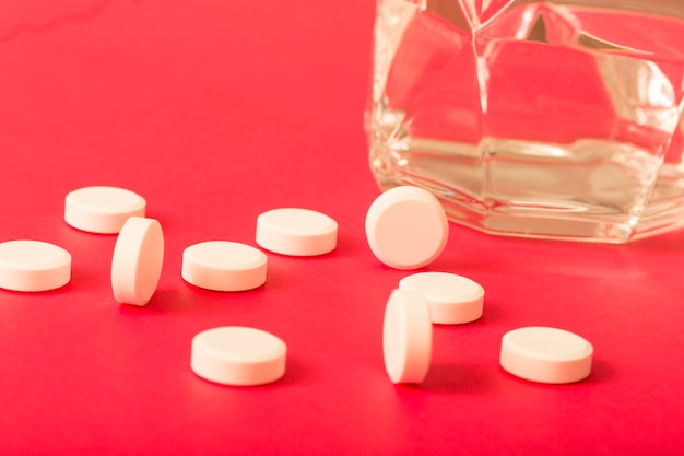 Free Photo circular white tablets with glass of water on dark background