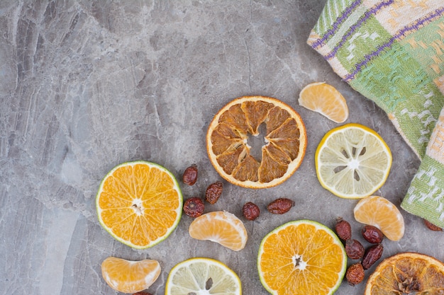 Citrus fruits slices and rosehips on stone background. 