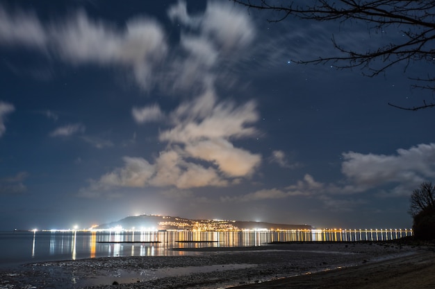 Free Photo city lights and night sky from the sandsfoot beach in dorset, uk