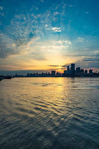 City Skyline By River Against cloudy Sky