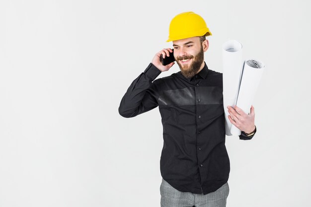 Civil engineer holding blueprint in his hand talking on cellphone