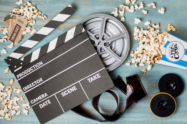 Clapperboard; popcorn; film stripe and cinema tickets on wooden desk