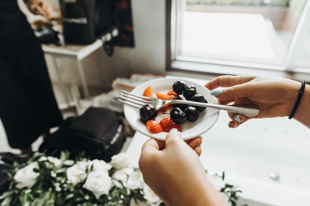 Free Photo classic banquette. woman holds little plate with fruits in her a