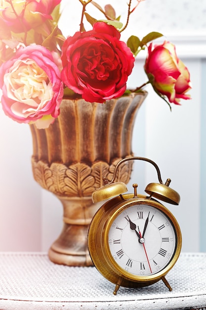 Free photo classic clock  watch in bright colorful retro interior behind red flowers