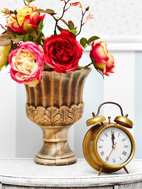 Free photo classic clock  watch in bright colorful retro interior behind red flowers