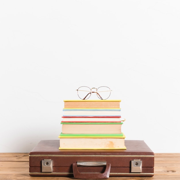 Free Photo classic eyeglasses on stack of books on vintage suitcase