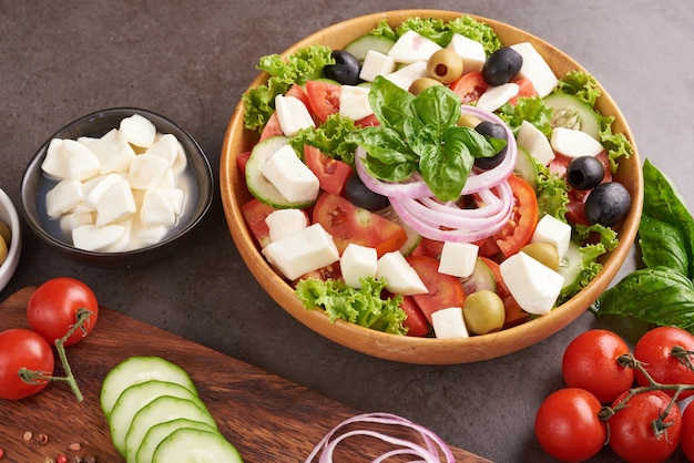 Free photo classic greek salad of fresh vegetables, cucumber, tomato, sweet pepper, lettuce, red onion, feta cheese and olives with olive oil. healthy food, top view