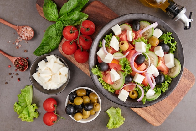 Free photo classic greek salad of fresh vegetables, cucumber, tomato, sweet pepper, lettuce, red onion, feta cheese and olives with olive oil. healthy food, top view