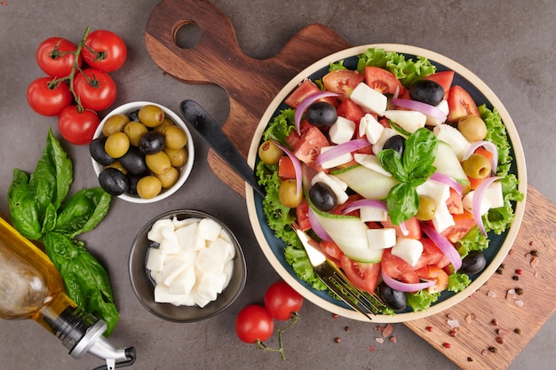 Free Photo classic greek salad of fresh vegetables, cucumber, tomato, sweet pepper, lettuce, red onion, feta cheese and olives with olive oil. healthy food, top view