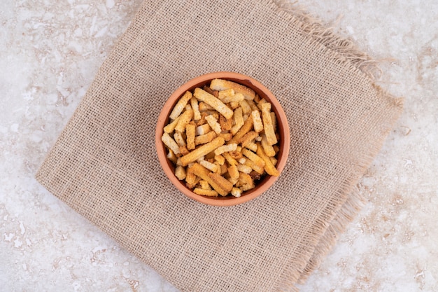 A clay bowl of breadsticks on a sackcloth