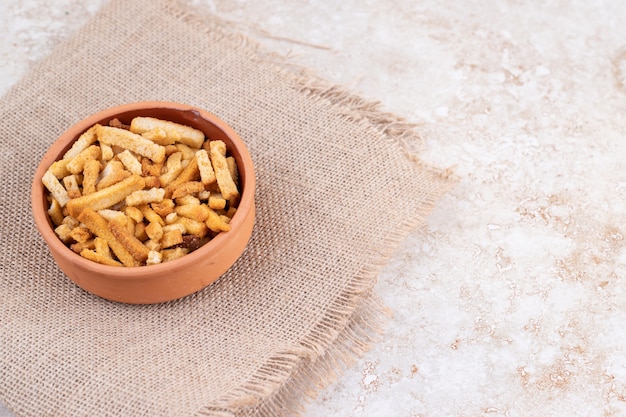 A clay bowl of breadsticks on a sackcloth