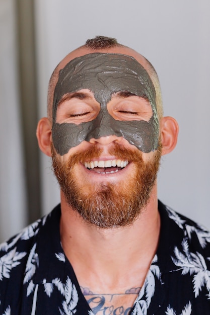 clay mask on young handsome mans face in beauty clinic