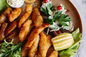 Free photo clay plate full of appetizers served with goldy chicken nuggets cooked with chrispy crust delicious canapes with herring and cherry tomatoes garlic sauce decorated with fresh salad and cheese