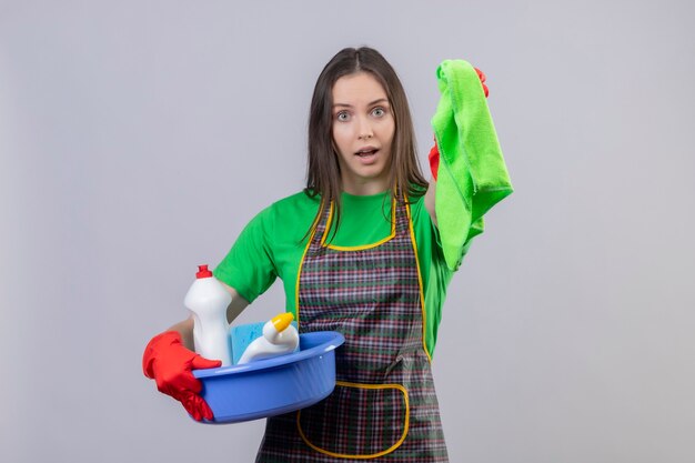  cleaning young woman wearing uniform in red gloves holding cleaning tools and holding out rag  on isolated white wall