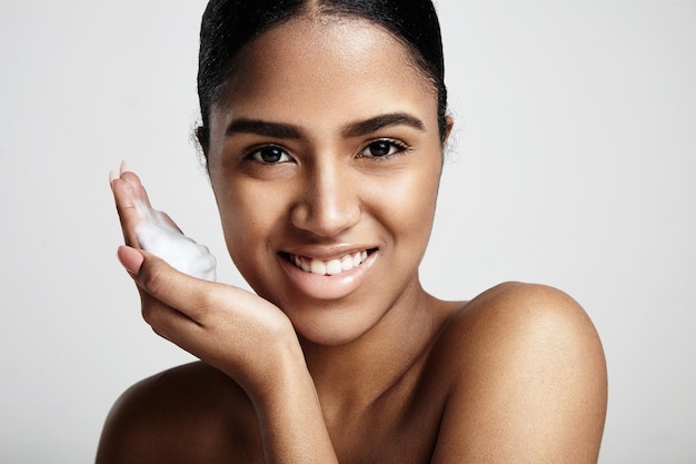 Cleansing skin concept smiling woman with a foam on a hand