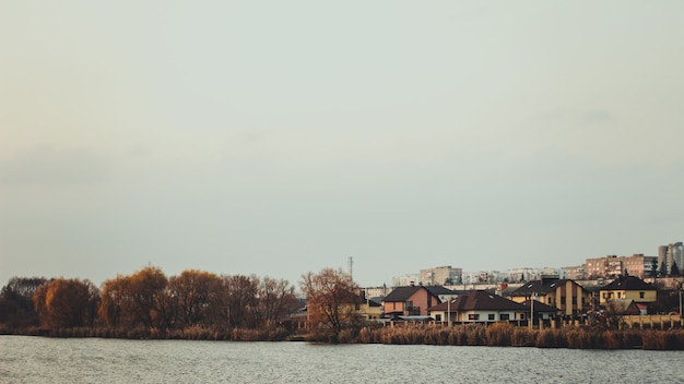 Free Photo clear lake surrounded by autumn trees and houses