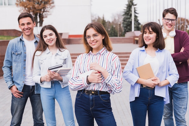 Clever men and smart women standing with books looking at camera