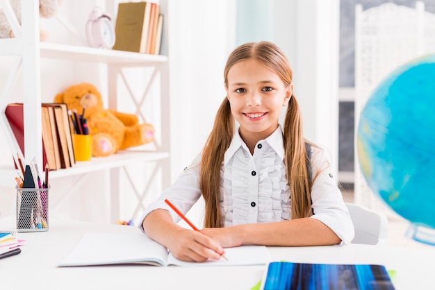 Clever schoolgirl sitting at desk