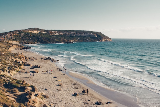 Cliff by the sandy seashore under a clear sky