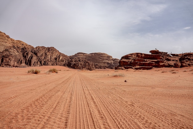 Cliffs and caves on a desert full of dry grass under a cloudy sky during daytime