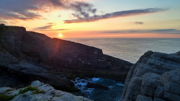 Cliffs surrounded by the sea under the sunlight during the sunset