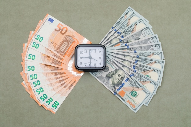 Free photo clock, dollar and euro bills on green grey table .