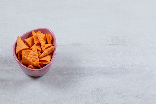 Cloe up photo of spicy chips in purple bowl on white.