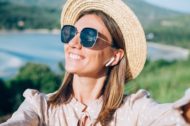 Close portrait of young woman with sunglasses and earrings at warm sunset in park