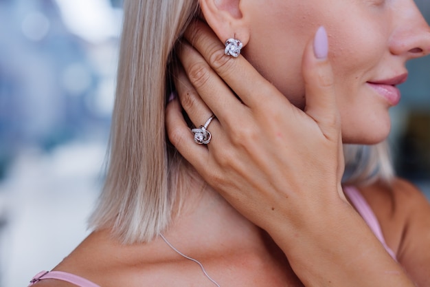 Free photo close shot of rich luxury woman in dress hand and ear wearing earrings and ring on finger