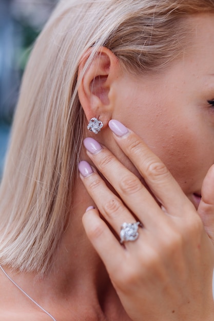 Free photo close shot of rich luxury woman in dress hand and ear wearing earrings and ring on finger