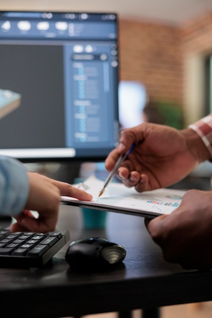 Free photo close up of 3d digital artists reviewing sketch scene plan and simulated render times, creative industry enthusiasts with cad open in background discussing technical issues while pointing at clipboard