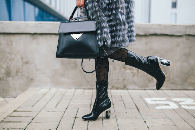 Free Photo close up accessories details of stylish woman walking in city in warm fur coat, winter season, cold weather, holding leather handbag, legs in boots, footwear street fashion trend