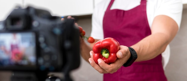 Free photo close-up adult male presenting bell pepper on camera