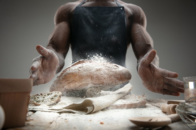 Close up of african-american man cooks fresh cereal, bread, bran on wooden table. Tasty eating, nutrition, craft product. Gluten-free food, healthy lifestyle, organic and safe manufacture. Handmade.