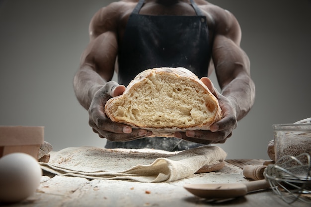 Free photo close up of african-american man cooks fresh cereal, bread, bran on wooden table. tasty eating, nutrition, craft product. gluten-free food, healthy lifestyle, organic and safe manufacture. handmade.