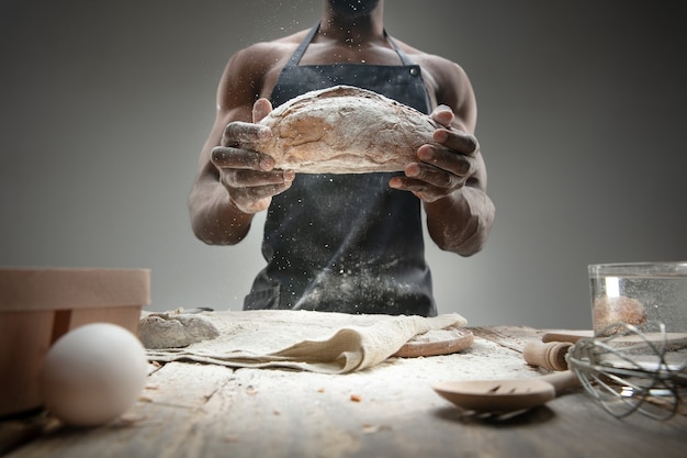 Close up of african-american man cooks fresh cereal, bread, bran on wooden table. Tasty eating, nutrition, craft product. Gluten-free food, healthy lifestyle, organic and safe manufacture. Handmade.