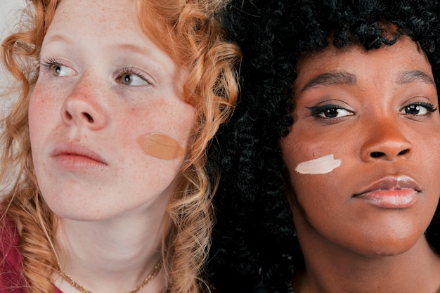 Free Photo close-up of an african and caucasian woman's face with skin tone foundation cream