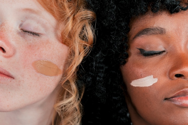 Free photo close-up of an african and caucasian woman's face with skin tone foundation cream