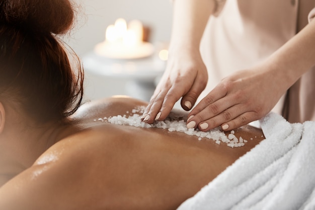 Close up of african woman relaxing enjoying spa health massage with sea salt.