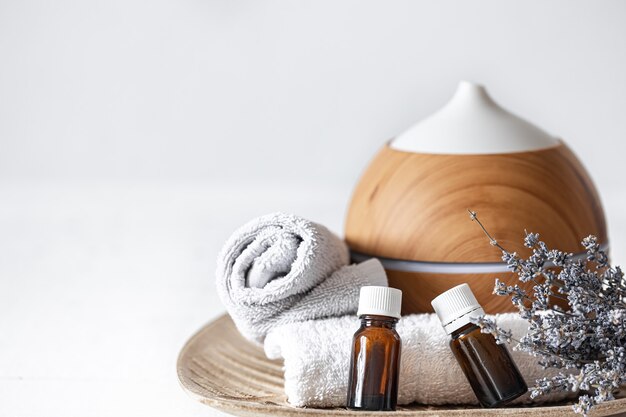 Close up of an air humidifier, natural aromatic oils, towels and lavender sprigs. Aromatherapy and health care concept background