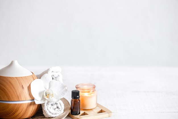 Close up of air humidifier, towel, aromatic oil and orchid flower. Aromatherapy and care and health concept background