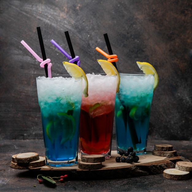 Close-up alcohol cocktails glasses of blue lagoon cocktail decorated with lemon and glass of cocktail with whiskey on a wooden stand