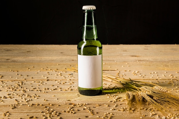 Free photo close-up of an alcoholic bottle and ears of wheat on wooden plank