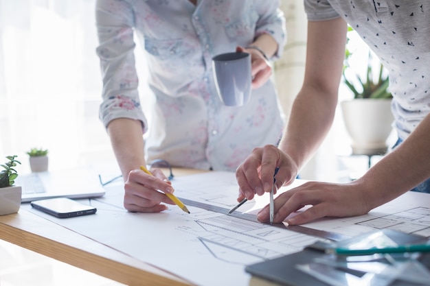 Free Photo close-up of architecture hands working on blueprint over wooden table at office